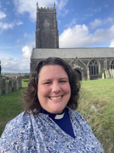 Revd Laura Bushell Hawke with a church behind her.